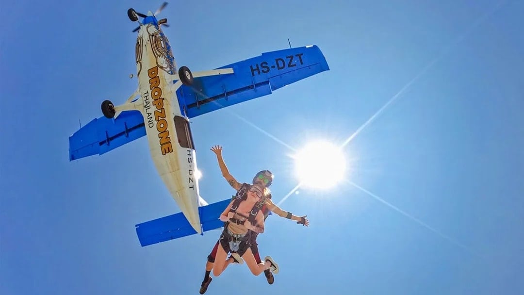 Tandem skydive over Pattaya from 13,000 ft with clear ocean view and airplane above.