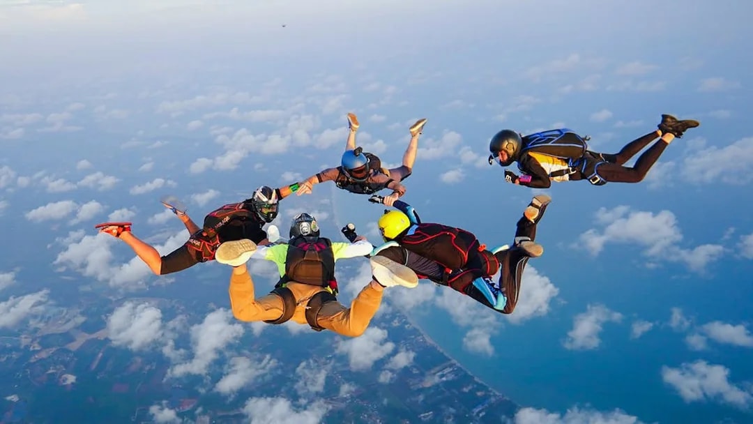 Skydivers in freefall over Pattaya coastline during tandem jump at 13,000 ft.