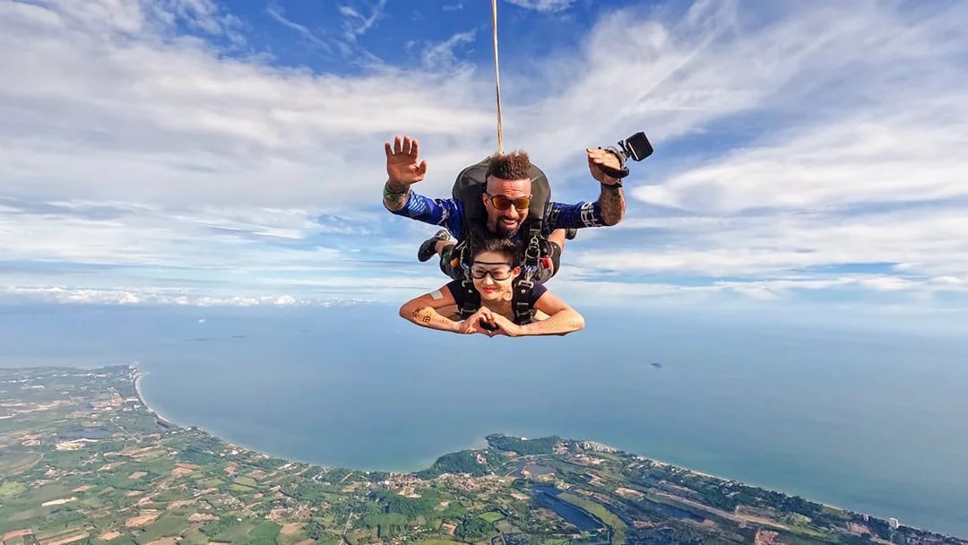 Skydivers above coastline and ocean, capturing breathtaking coastal view.