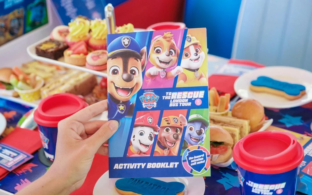 Paw Patrol activity booklet on Brigit’s Afternoon Tea Bus Tour table with themed snacks.