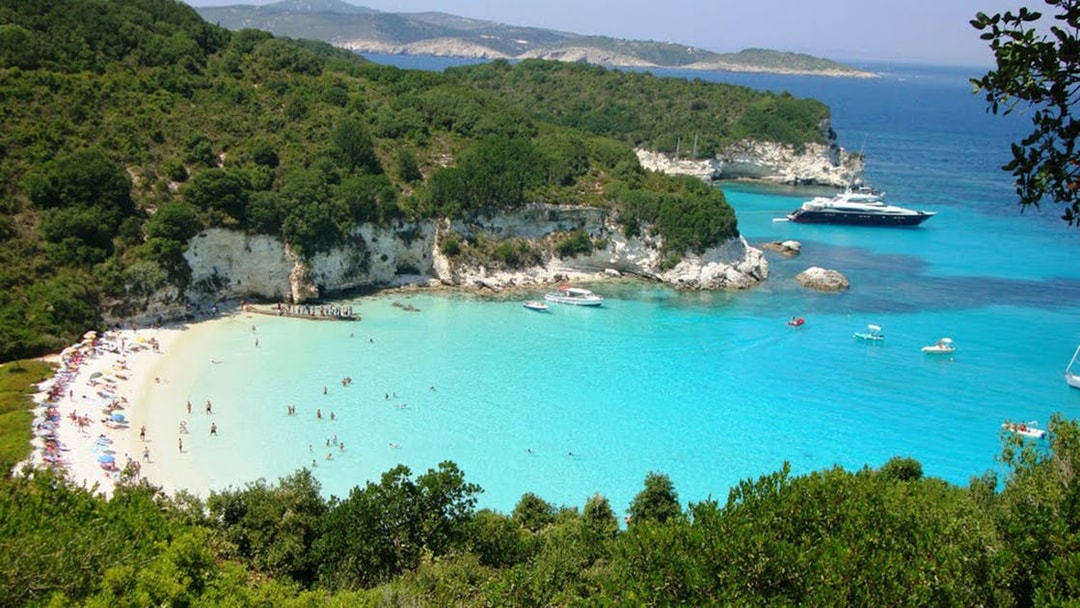 Paxos beach with turquoise waters and boats, part of the Paxos, Antipaxos & Blue Caves Cruise from Corfu.