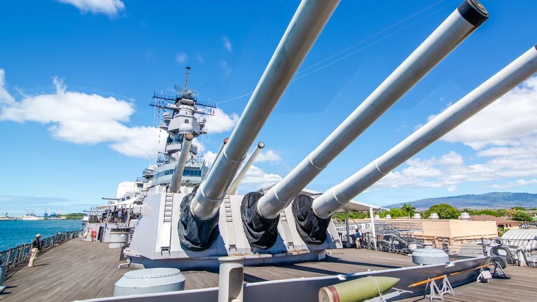 Missouri Battleship Memorial deck with large naval guns under a clear blue sky.