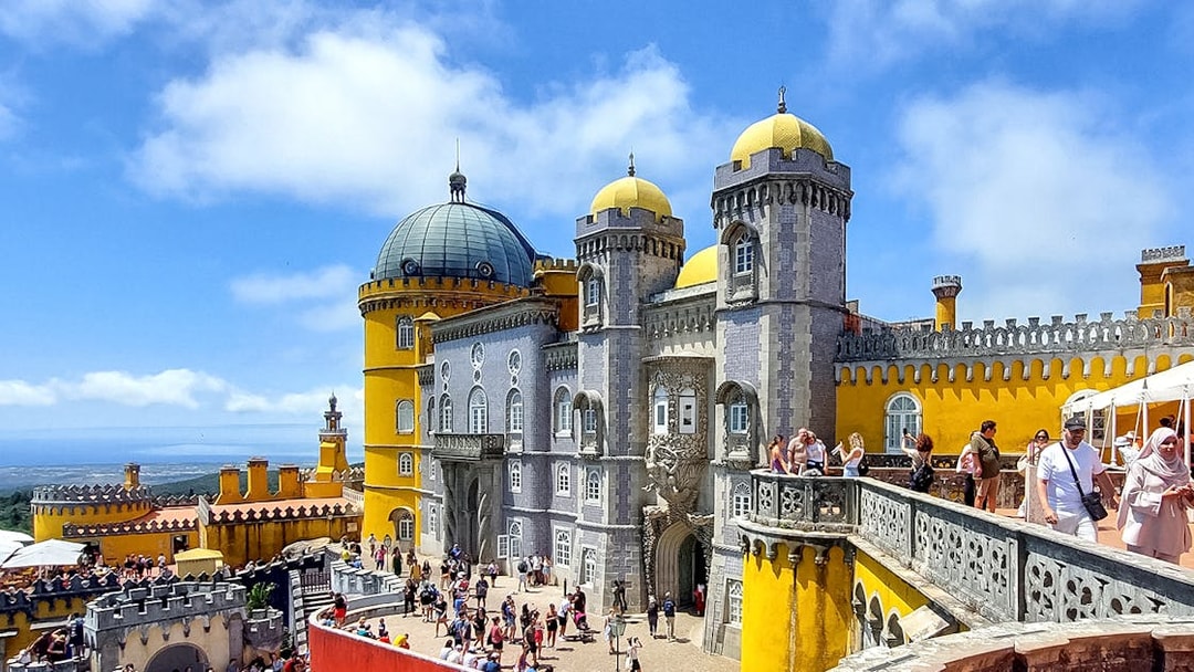 Pena Palace in Sintra with tourists exploring the colorful architecture.