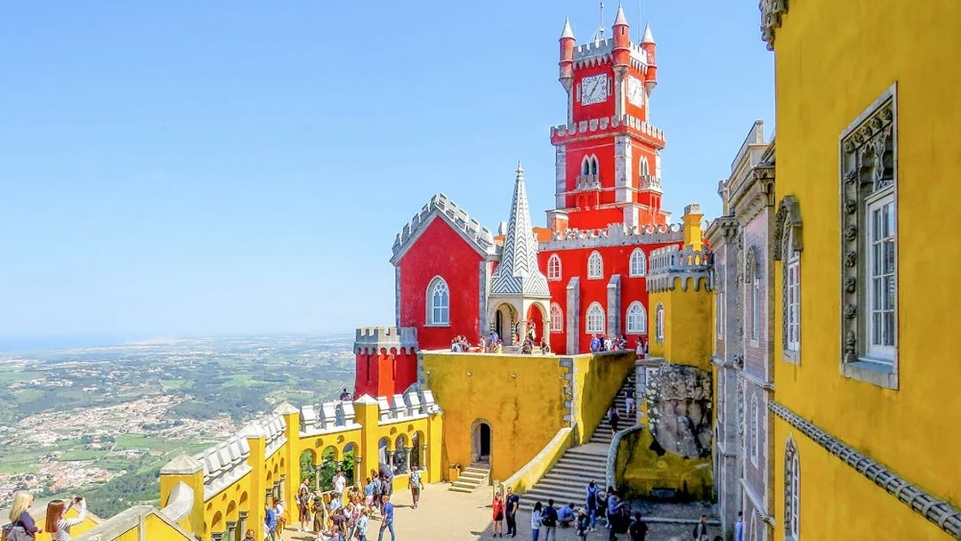 Pena Palace in Sintra with tourists exploring the colorful architecture.
