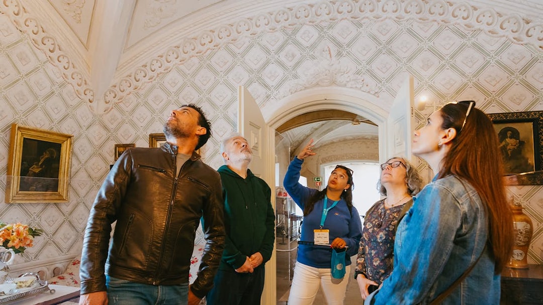 Tour group inside Pena Palace, Sintra, observing ornate ceiling details.