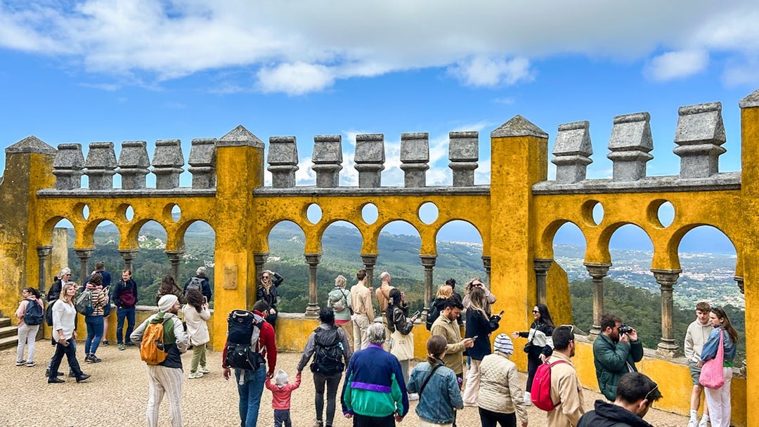 Tourists exploring the terrace of Pena Palace with scenic views in Sintra, Portugal.