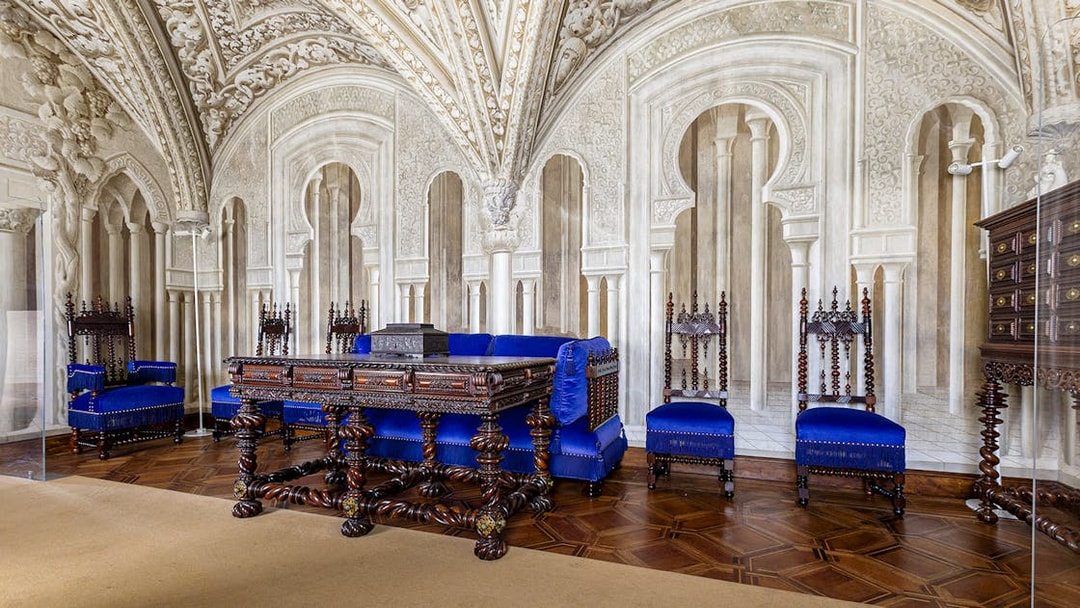 Ornate sitting room in Pena Palace with carved wooden furniture and blue upholstery.