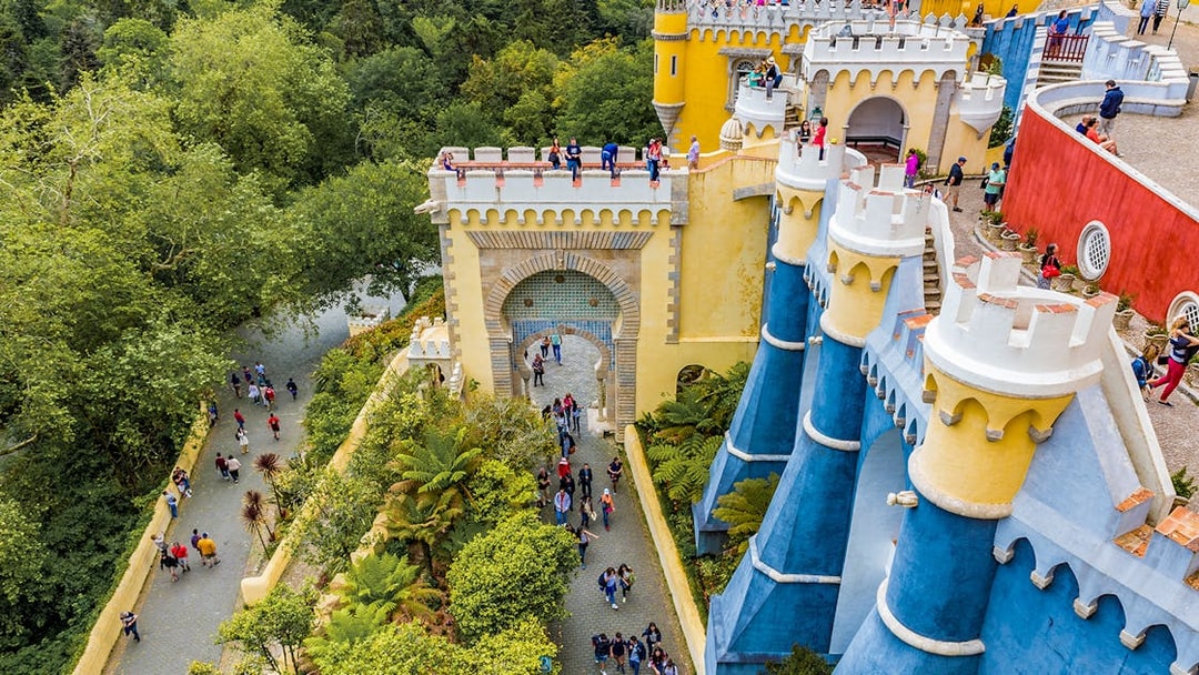 Visitors exploring the colorful architecture of the National Palace of Pena in Sintra, Portugal.