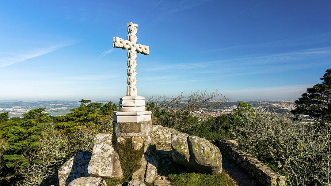 Stone cross at Cruz Alta viewpoint near Pena Palace, overlooking Sintra landscape.