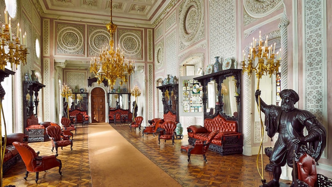 Luxurious interior of Quinta da Regaleira with ornate chandeliers and red leather seating, Sintra, Portugal.