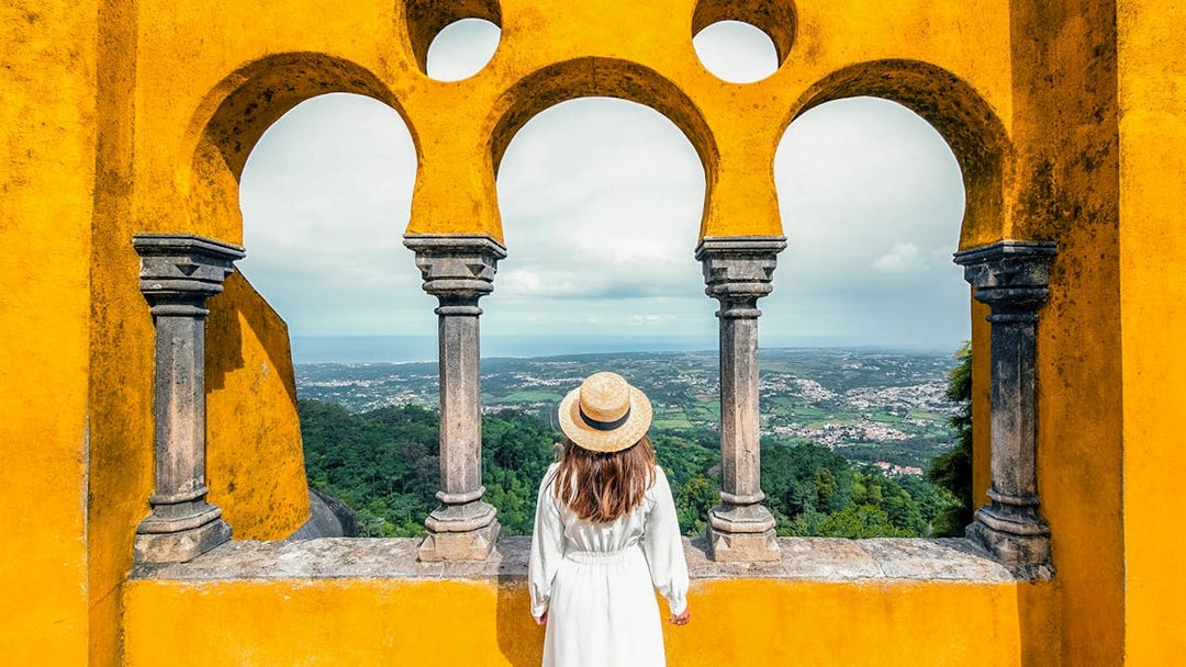 Person viewing landscape through arches at Pena Palace, Sintra, Portugal.