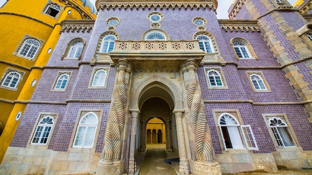 Pena Palace entrance with ornate columns and colorful facade in Sintra, Portugal.
