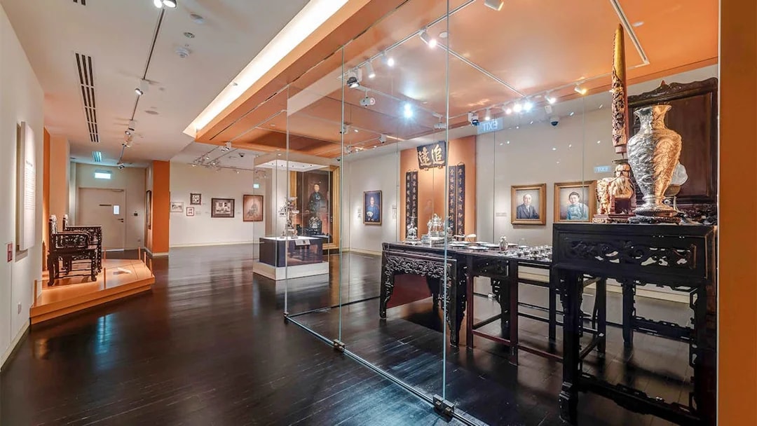 Peranakan Museum gallery with traditional artifacts and portraits on display.