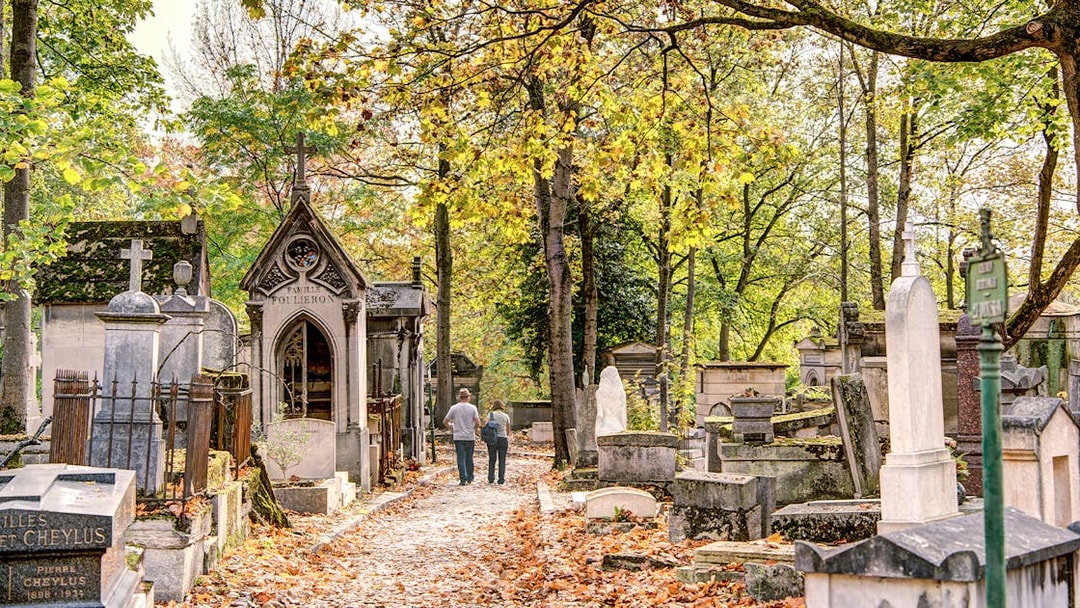 Père Lachaise Cemetery path with historic graves and autumn leaves, Paris.