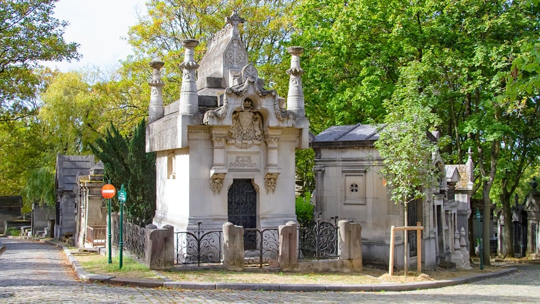 Père Lachaise Cemetery mausoleum surrounded by trees and cobblestone path.