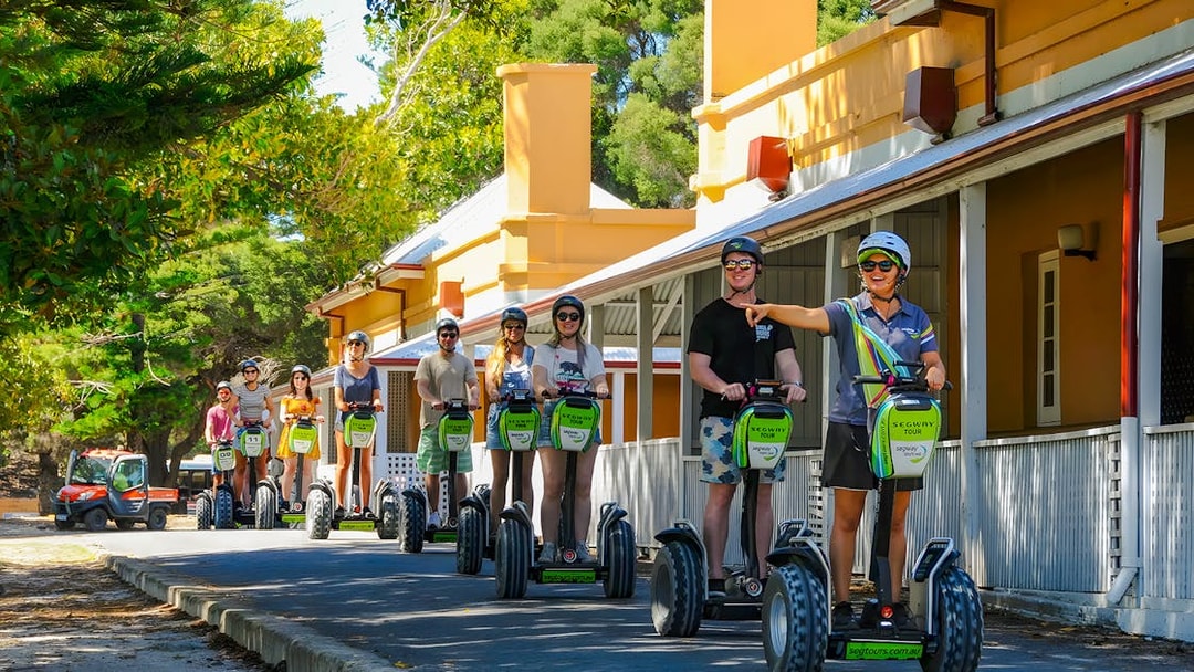 People on Segways during a tour on Rottnest Island, passing historic buildings.
