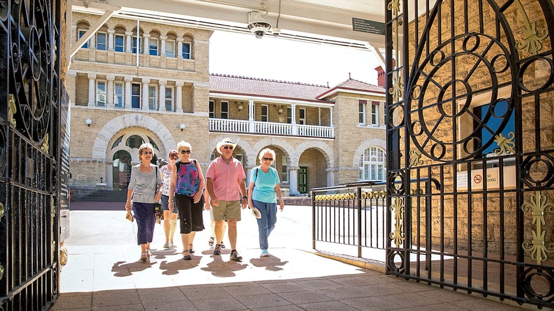 Visitors walking through ornate gates at a historic building in Perth's Kings Park.