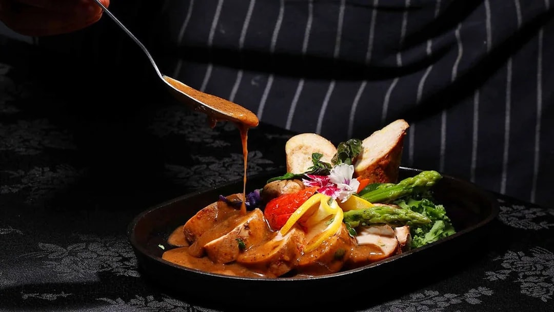 Chef adding sauce to a dish at ARAS restaurant, KL Tower, Kuala Lumpur.