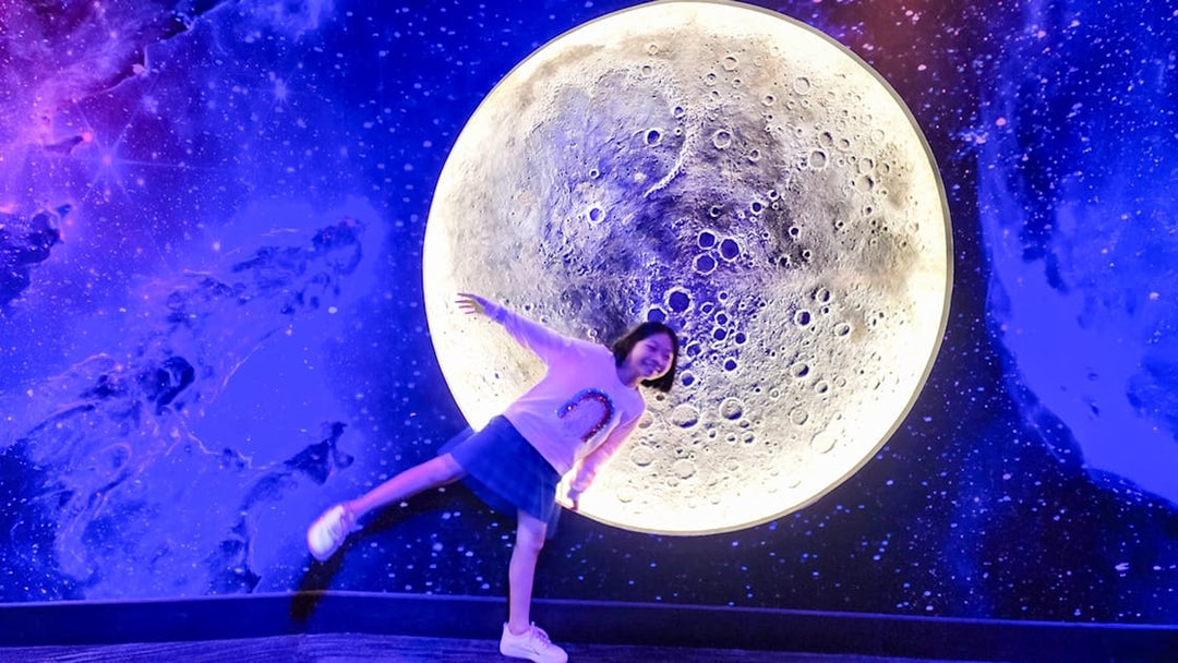 Child posing in front of a moon exhibit at Petrosains, The Discovery Centre, Kuala Lumpur.