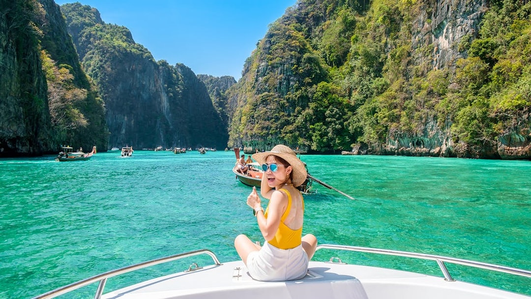 Woman on speedboat in turquoise waters of Phi Phi Island, surrounded by cliffs.