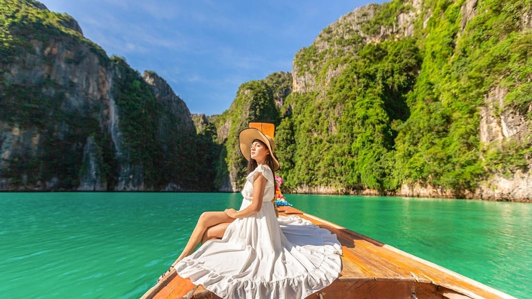 Woman in white dress on longtail boat, Maya Bay, Phi Phi Islands tour.
