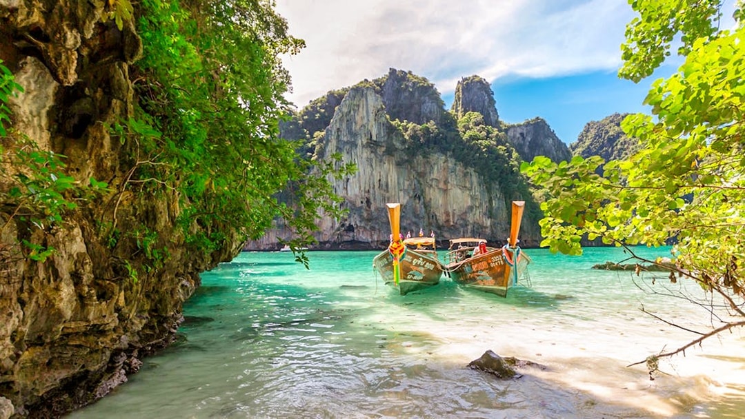 Longtail boats on Maya Bay beach, Bamboo Island, Phi Phi with limestone cliffs.
