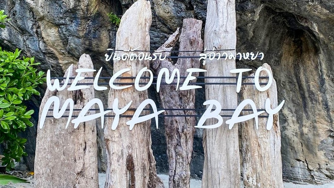 Welcome sign at Maya Bay Island with wooden posts and rocky background.