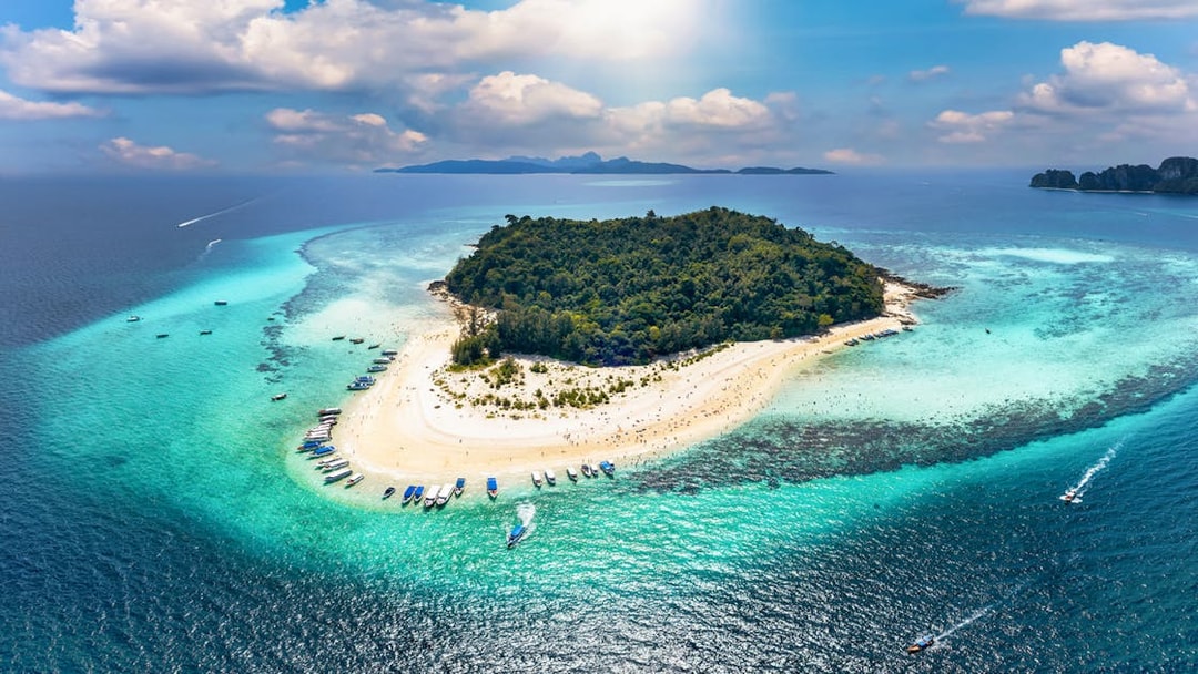 Aerial view of Bamboo Island with boats along the sandy shore and turquoise waters.