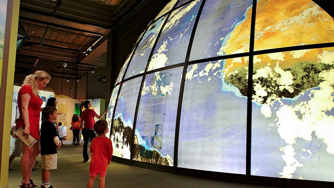 Visitors exploring large illuminated globe at Franklin Institute.