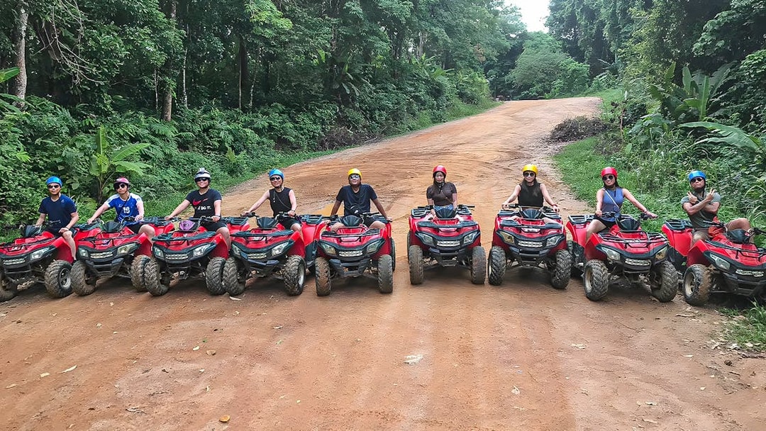 Tourists on ATVs in Phuket, riding through lush forest trails.
