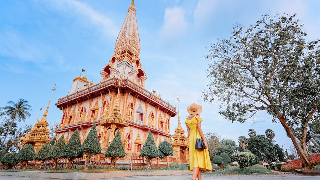 Woman in yellow dress visiting Wat Chalong temple in Phuket on a guided tour.