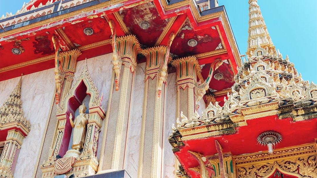 Wat Chalong temple architecture in Phuket, featuring ornate red and gold details.