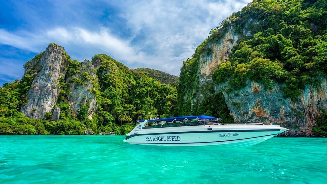 Speedboat on turquoise water near rocky islands in Phi Phi, Thailand.