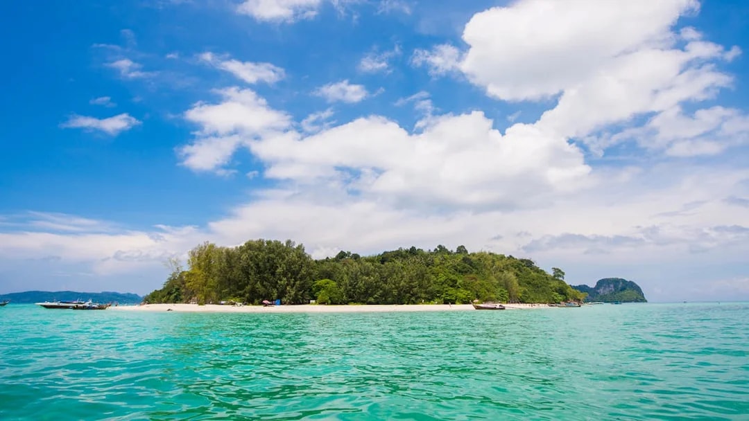Phi Phi island beach with turquoise water and boats during sunrise tour.