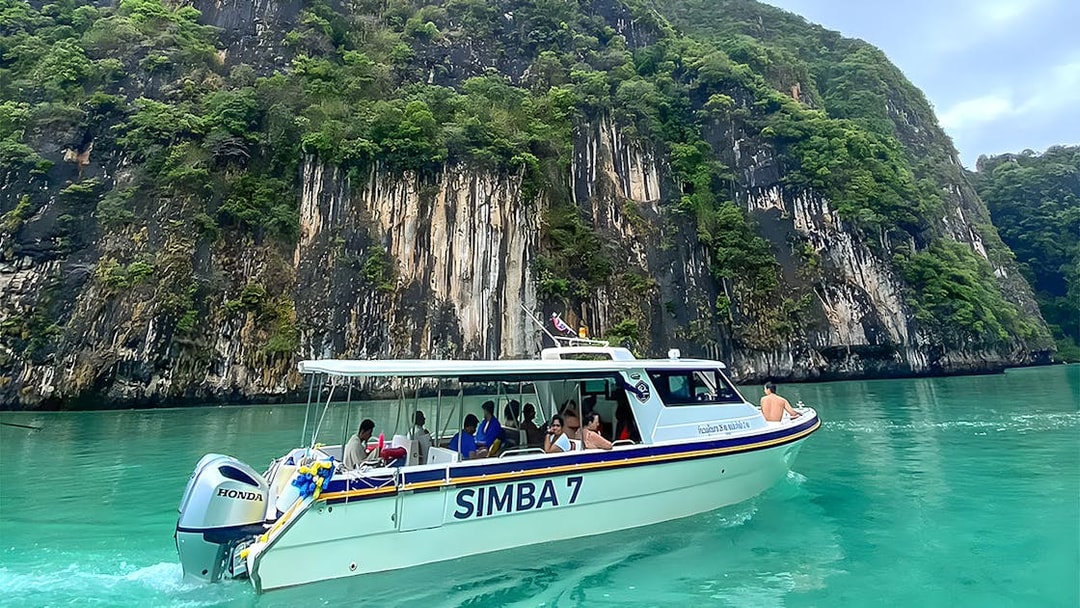 Speedboat on Phi Phi Sunrise tour near limestone cliffs, Thailand.