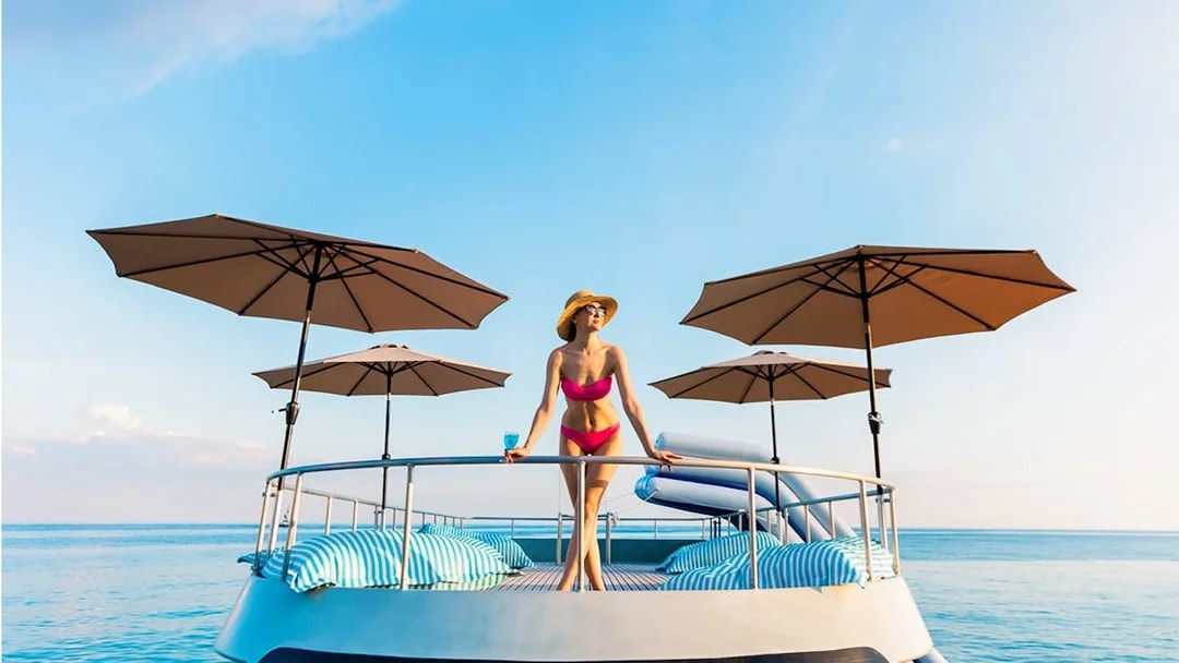 Tourist on deck of whale shark fleet boat with umbrellas and ocean view.