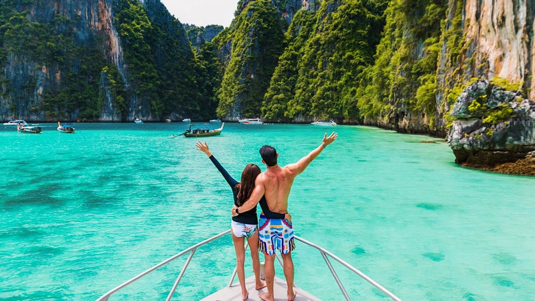 Couple on boat exploring Pileh Lagoon surrounded by cliffs and turquoise water.