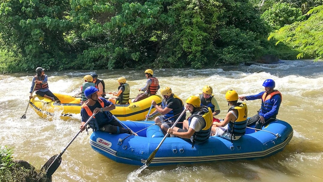 Rafting adventure on a river in Phuket with participants in helmets and life jackets.