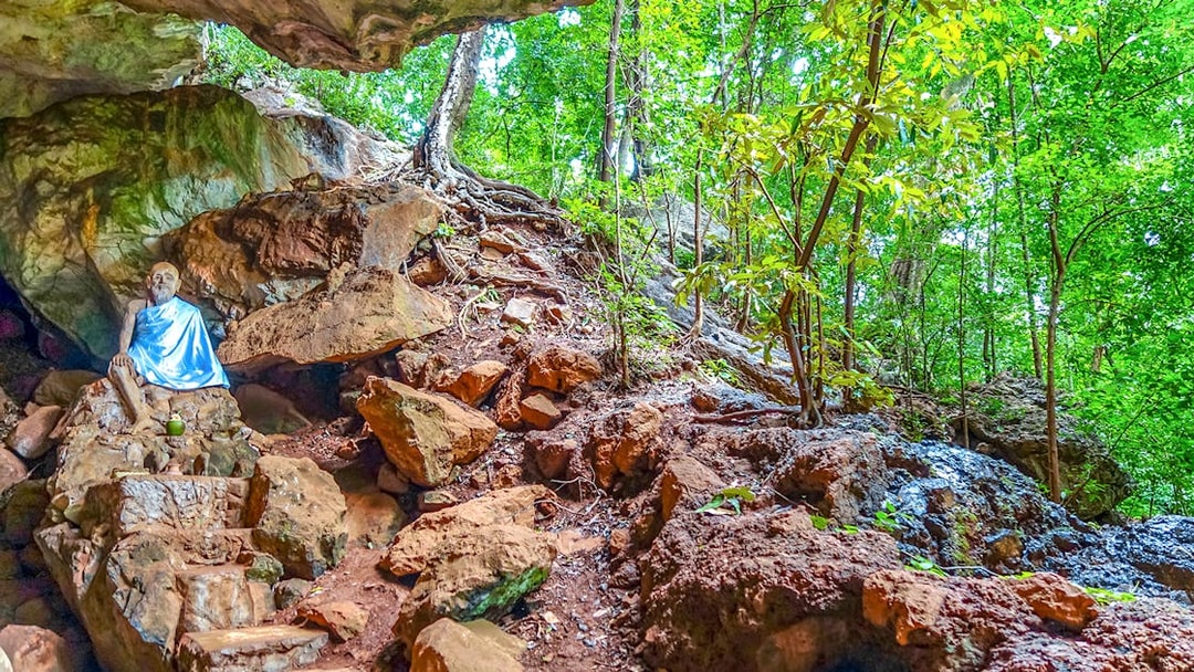 Monk statue in a rocky forest setting in Phuket, Thailand.