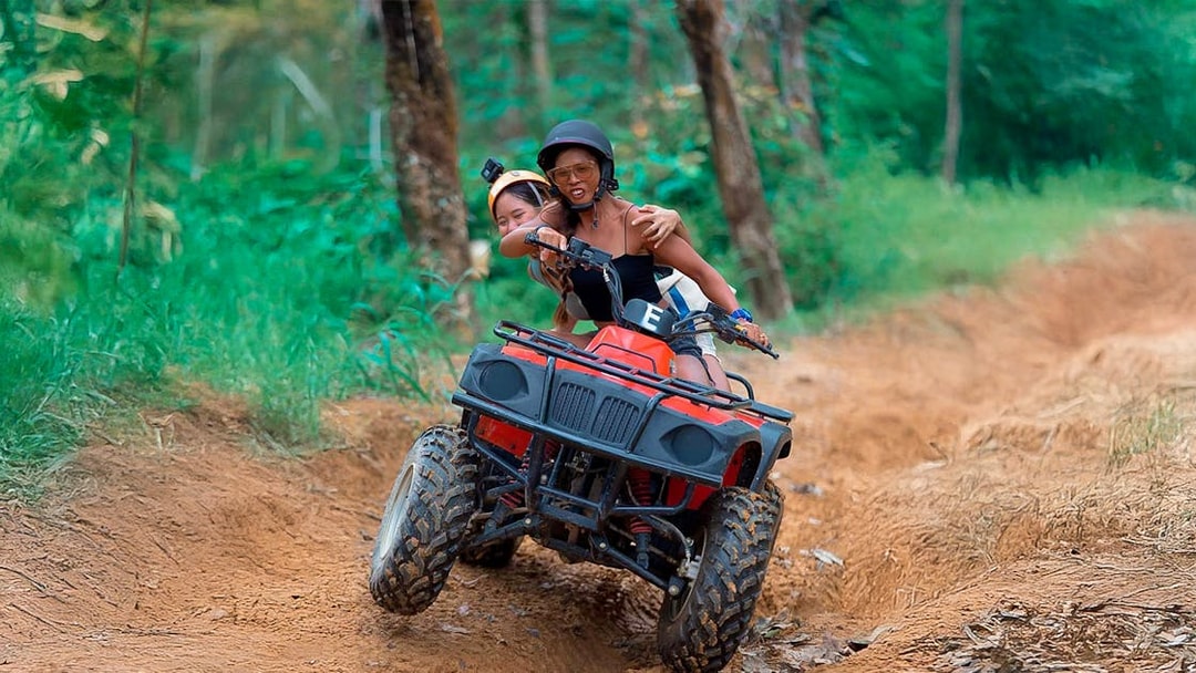 ATV riders navigating a dirt trail in Phuket forest.