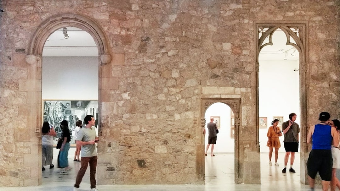 Visitors exploring exhibits at Picasso Museum Barcelona through stone archways.