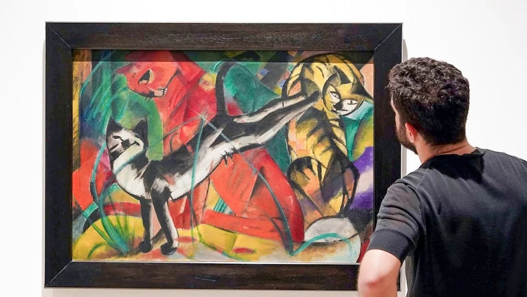 Visitor admiring a colorful painting of cats at Picasso Museum, Malaga.