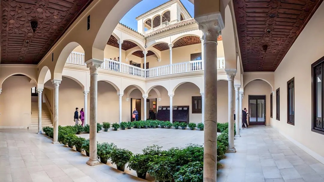 Courtyard of the Picasso Museum in Malaga with arches and potted plants.