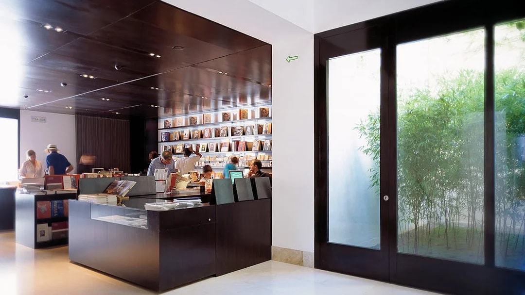 Visitors browsing books at Picasso Museum gift shop in Malaga, Spain.