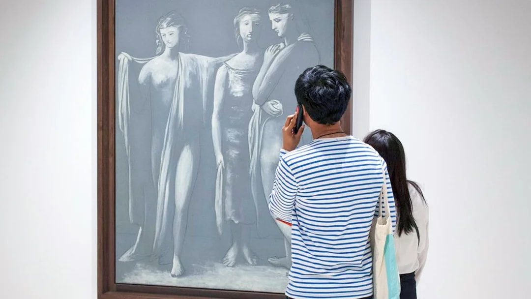 Visitor using audio guide in front of Picasso artwork at Picasso Museum Malaga.