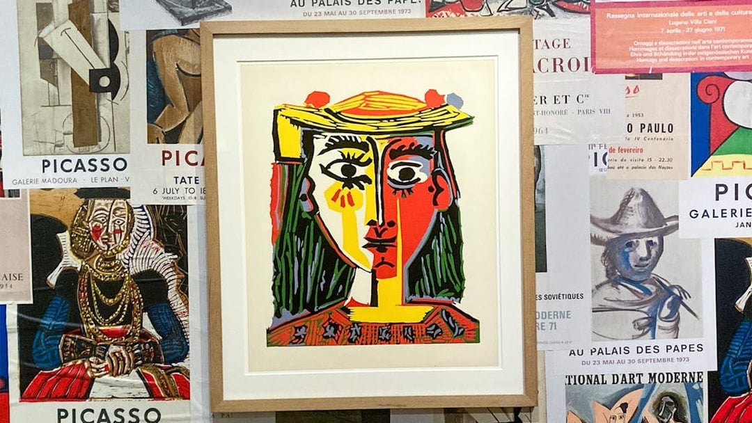 Framed Picasso painting on a wall of exhibition posters at the Picasso Museum.