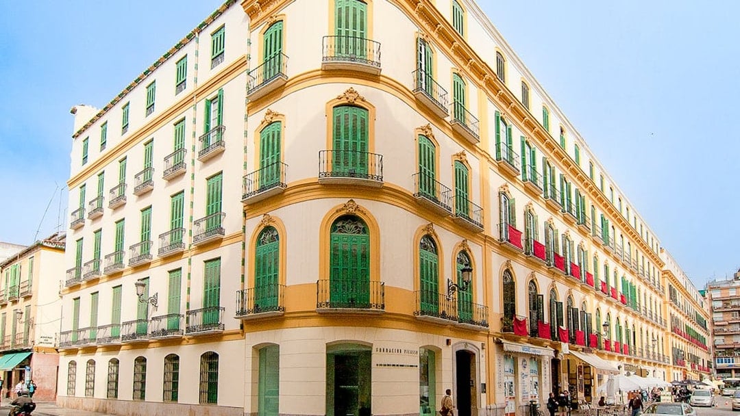 Facade of Picasso's Birthplace Museum in Málaga with green shutters and balconies.