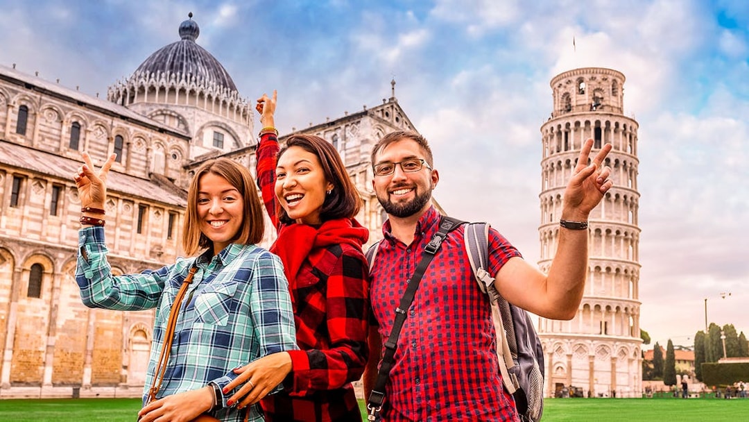 Tourists posing in front of Pisa Cathedral and Leaning Tower during guided tour.