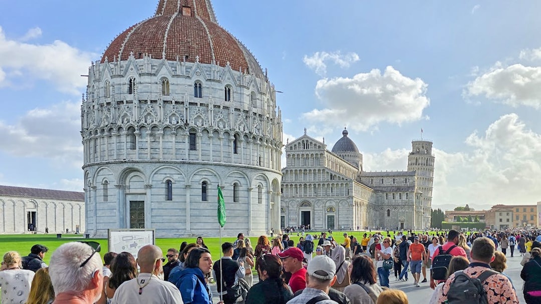 Visitors walking past the Pisa Baptistery towards the Cathedral in Italy.