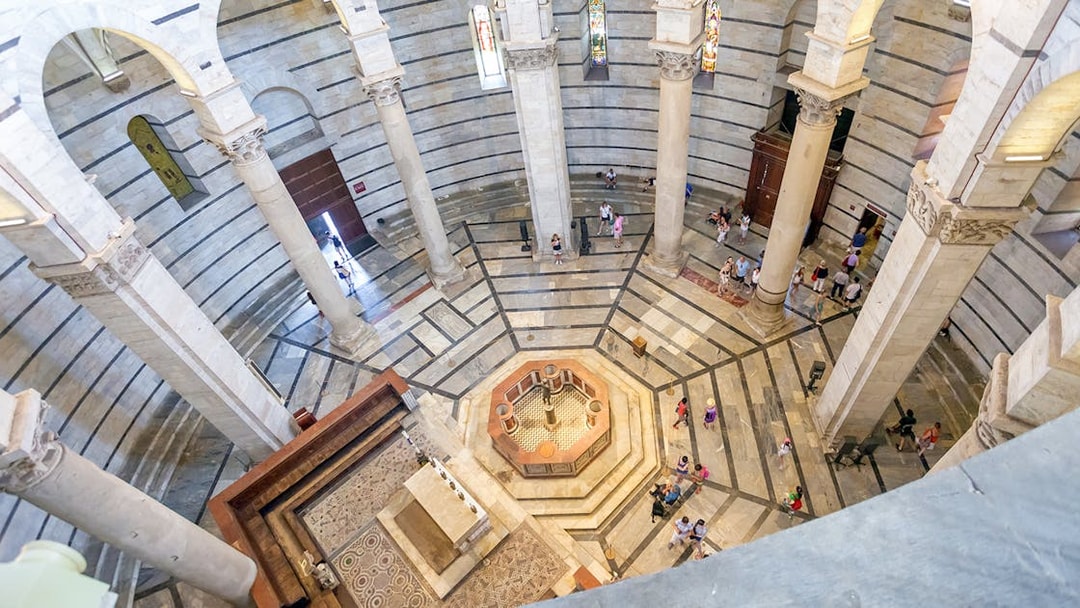 Circular interior of St. John's Baptistery in Pisa with columns and mosaic floor.